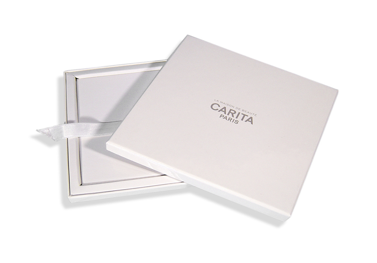CARITA - Boîte cloche contrecollée rembordée d’un papier couché – impression offset 1 couleur – pelliculage brillant – grille de calage « trottoir » + cale intérieure – ruban extracteur.